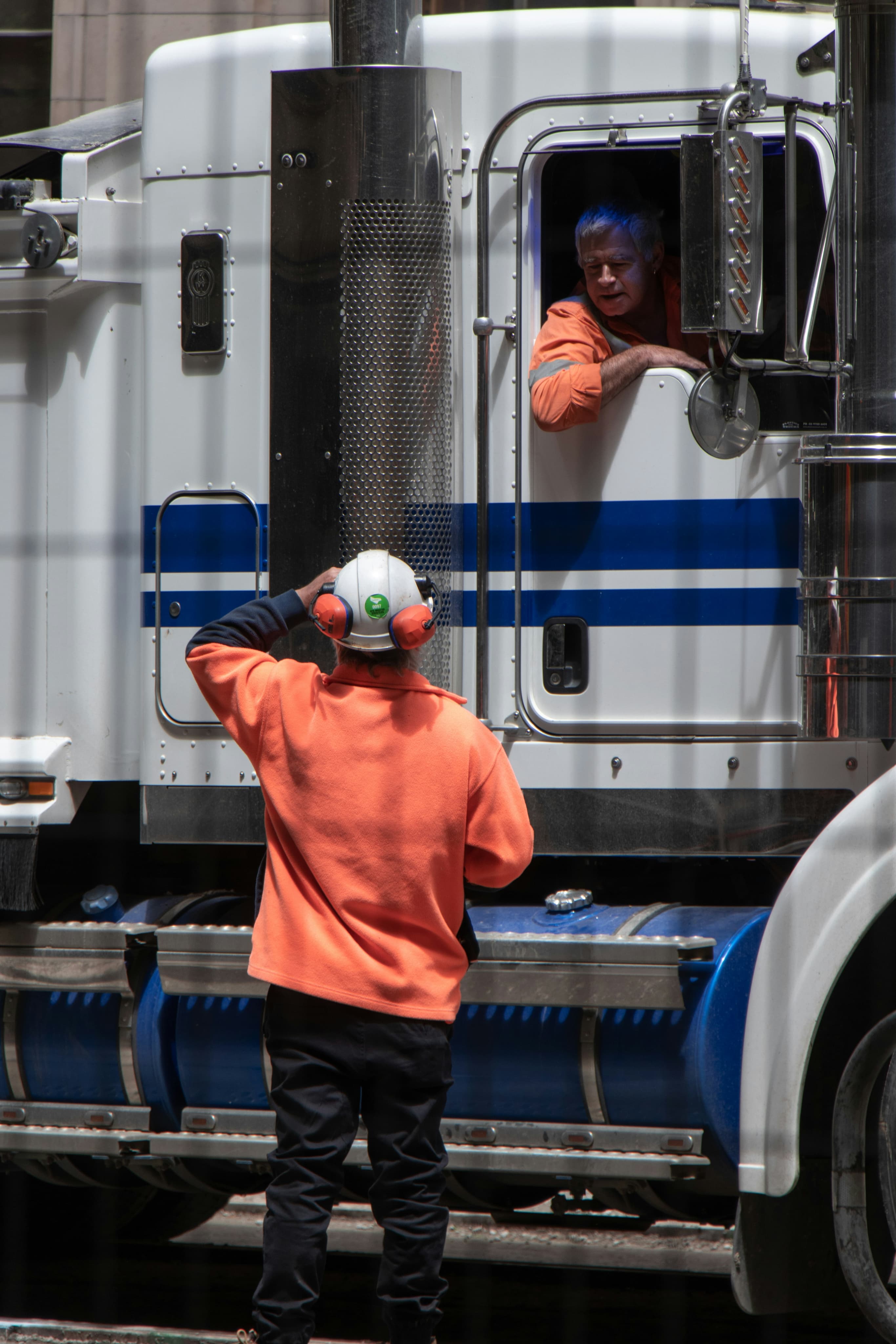 Mechanic helping the truck driver from outside of the cabin.